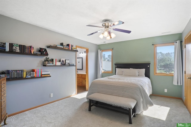 carpeted bedroom featuring ceiling fan, connected bathroom, and multiple windows