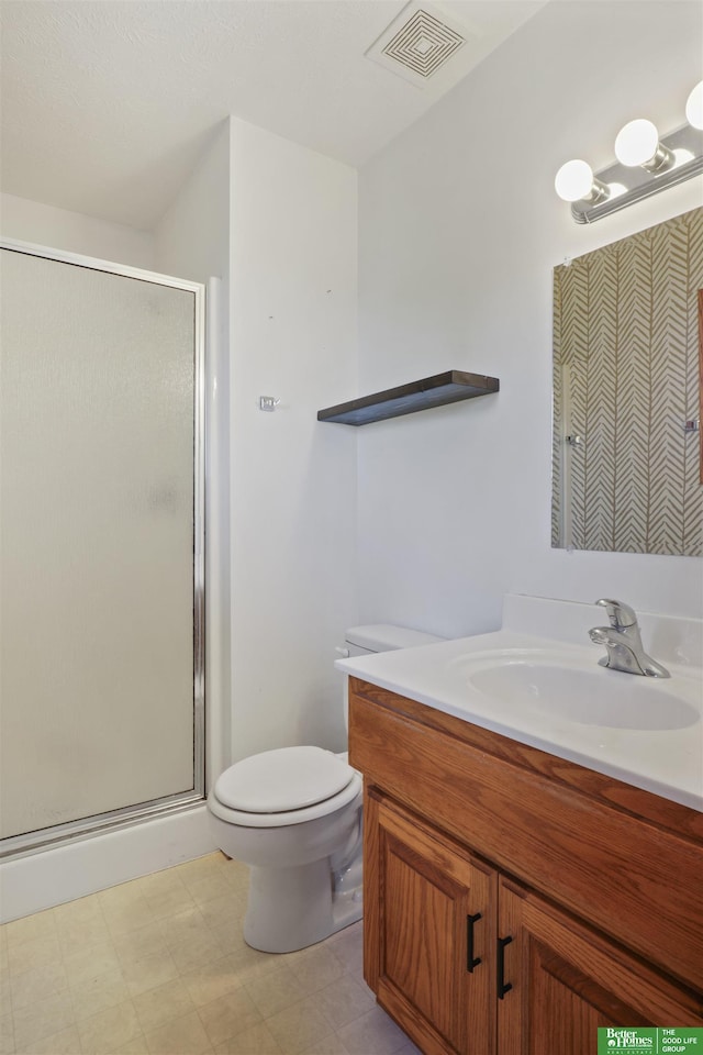 bathroom featuring vanity, a shower with shower door, and toilet