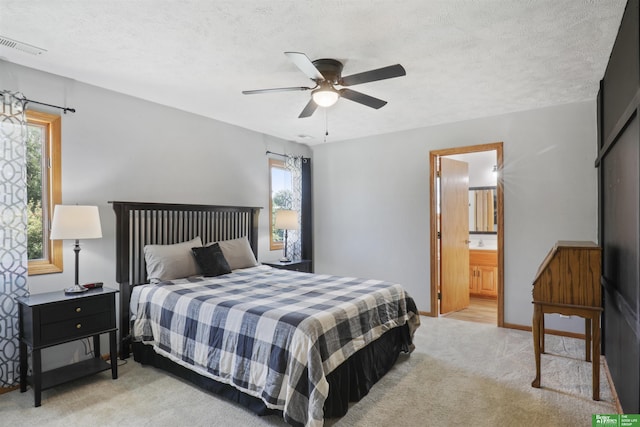 carpeted bedroom with ceiling fan, connected bathroom, and a textured ceiling