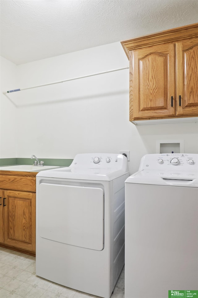 laundry area featuring cabinets, a textured ceiling, and washer and clothes dryer