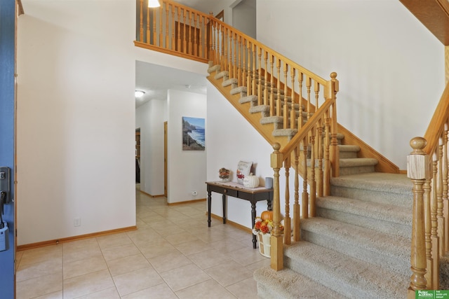 staircase with a high ceiling and tile patterned flooring