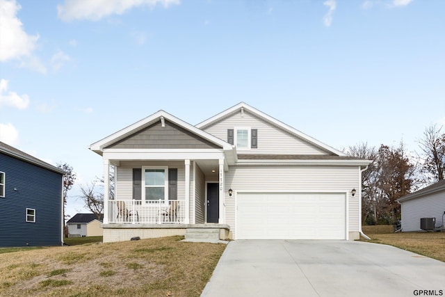 view of front of property with a garage, a front yard, central air condition unit, and covered porch