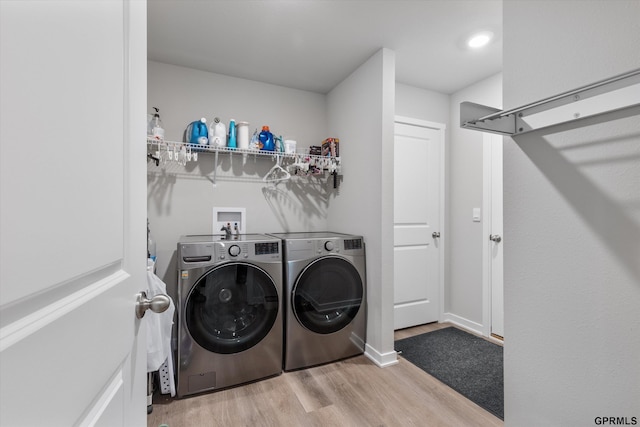 laundry room with light wood-type flooring and washer and clothes dryer