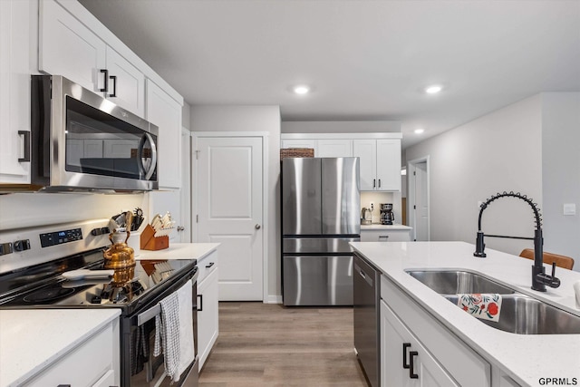 kitchen with white cabinetry, sink, stainless steel appliances, and light hardwood / wood-style floors