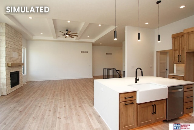 kitchen with pendant lighting, sink, dishwasher, a large fireplace, and a center island with sink