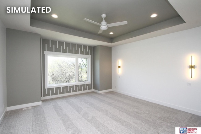 carpeted empty room with ceiling fan and a raised ceiling