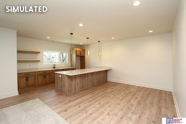 kitchen featuring sink, decorative light fixtures, kitchen peninsula, and light wood-type flooring