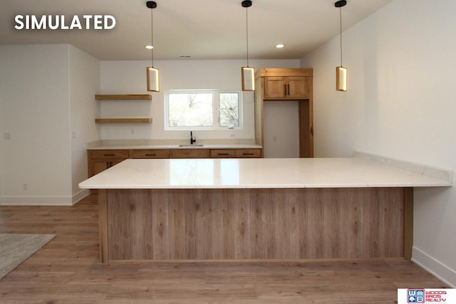 kitchen with hanging light fixtures, sink, light hardwood / wood-style flooring, and kitchen peninsula