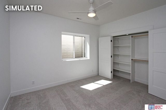 unfurnished bedroom featuring a barn door, carpet flooring, ceiling fan, and a closet