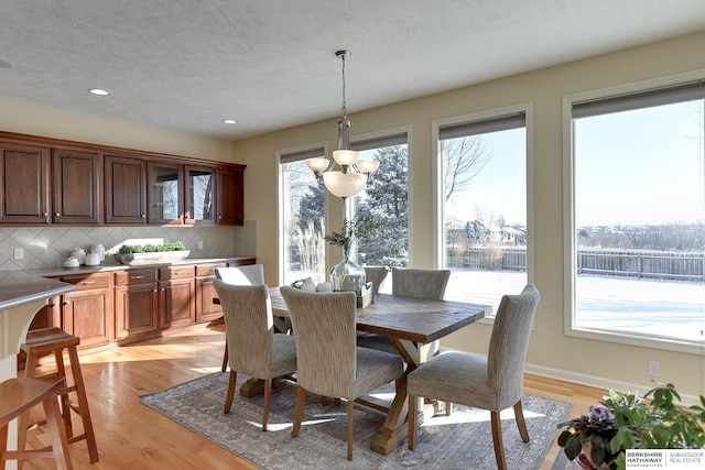 dining space featuring a notable chandelier, a textured ceiling, and light wood-type flooring