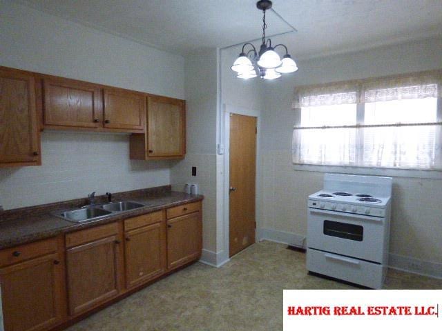 kitchen with sink, electric range, a chandelier, and a healthy amount of sunlight