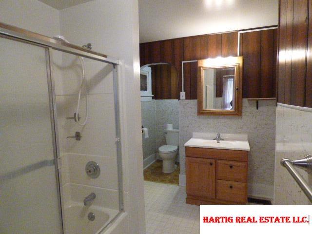 full bathroom with enclosed tub / shower combo, vanity, and toilet