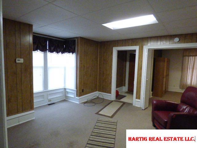 unfurnished living room with a paneled ceiling, wood walls, and carpet flooring