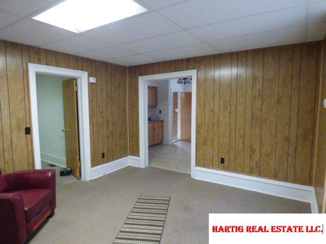 interior space with carpet, a drop ceiling, and wood walls