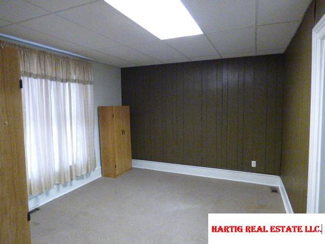 spare room with a paneled ceiling and wood walls