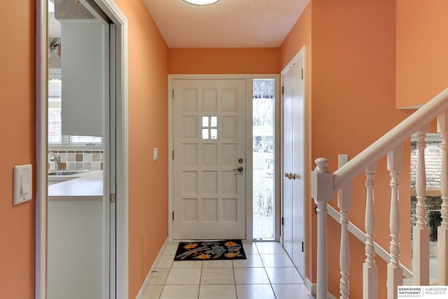 tiled foyer entrance with sink and a textured ceiling