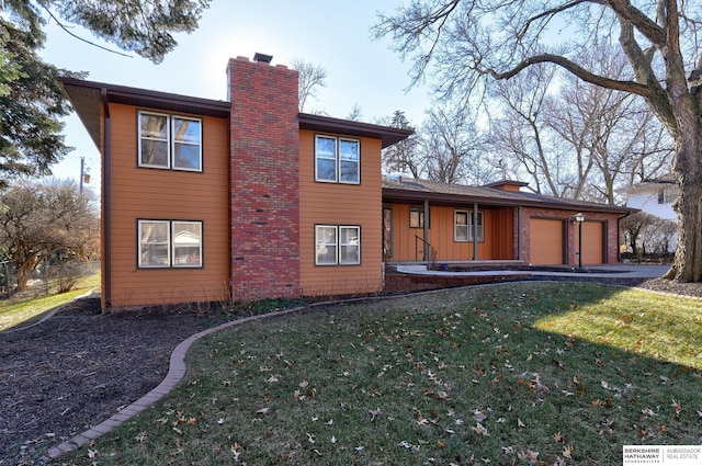 rear view of house featuring a garage and a lawn