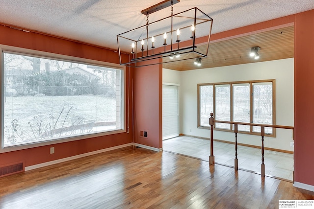 unfurnished dining area with hardwood / wood-style floors, track lighting, and a textured ceiling