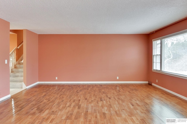 unfurnished room with light hardwood / wood-style floors and a textured ceiling