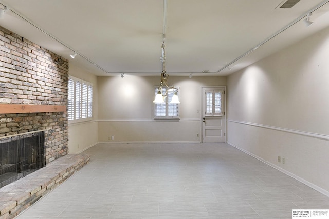 unfurnished dining area with a fireplace and track lighting