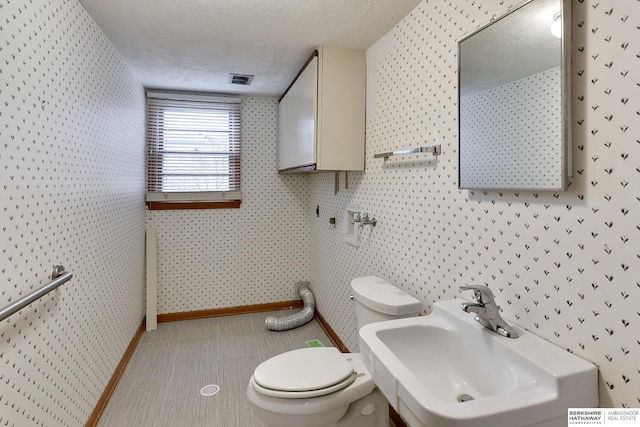 bathroom with sink, a textured ceiling, and toilet