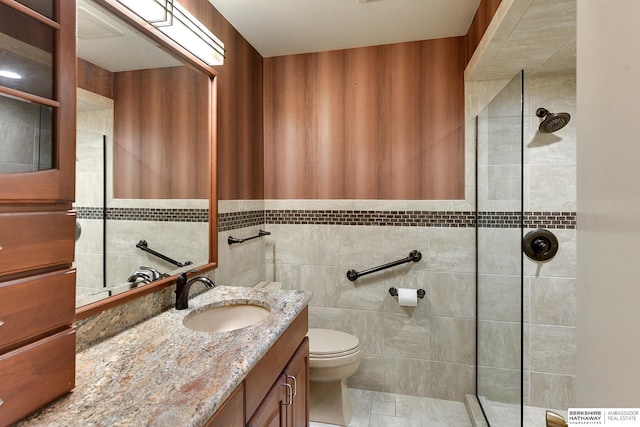 bathroom with tiled shower, vanity, toilet, and tile walls