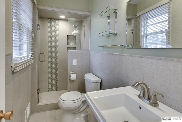 bathroom with a healthy amount of sunlight, sink, tile walls, and an enclosed shower