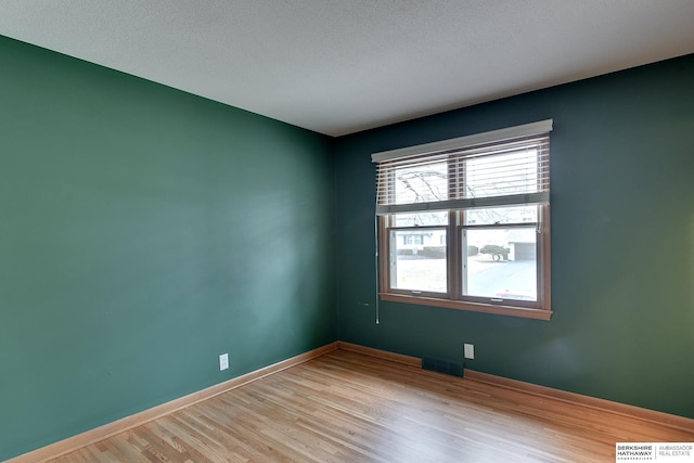 spare room with a textured ceiling and light hardwood / wood-style floors