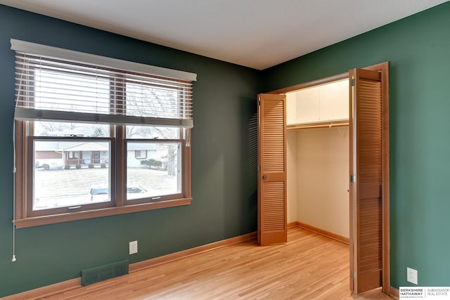 unfurnished bedroom with a closet, multiple windows, and light wood-type flooring