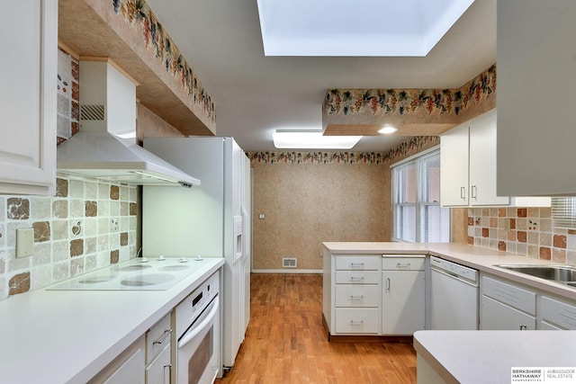 kitchen with white cabinetry, light hardwood / wood-style floors, kitchen peninsula, white appliances, and wall chimney exhaust hood