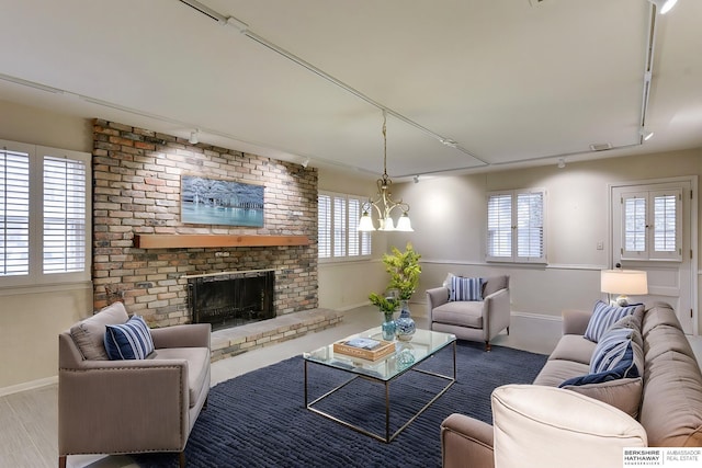 living room with an inviting chandelier, a fireplace, a healthy amount of sunlight, and track lighting