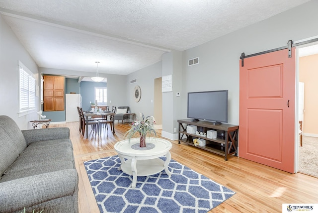 living room featuring a barn door, hardwood / wood-style floors, and a textured ceiling