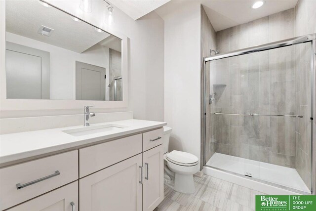 bathroom with a shower with door, vanity, and toilet