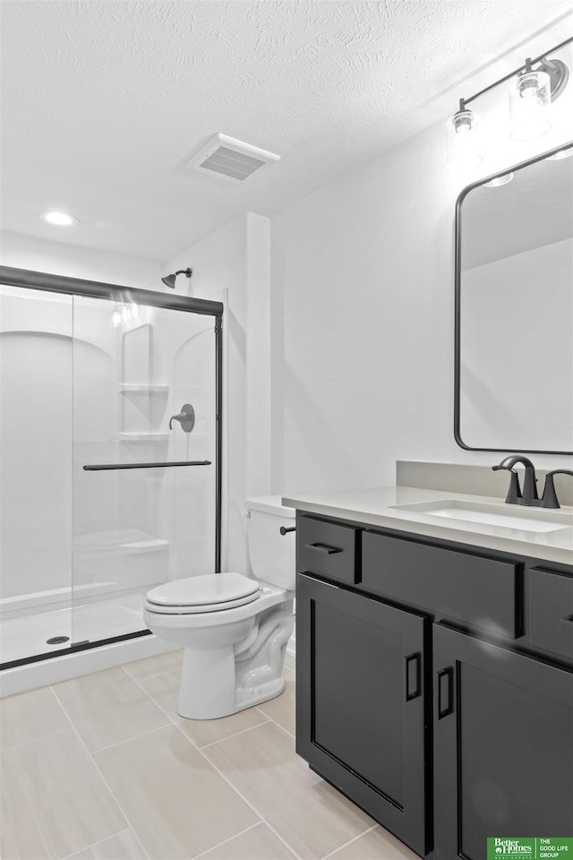 bathroom featuring vanity, toilet, a shower with door, and a textured ceiling