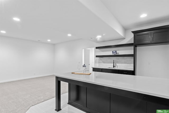 kitchen featuring sink, decorative backsplash, and light colored carpet