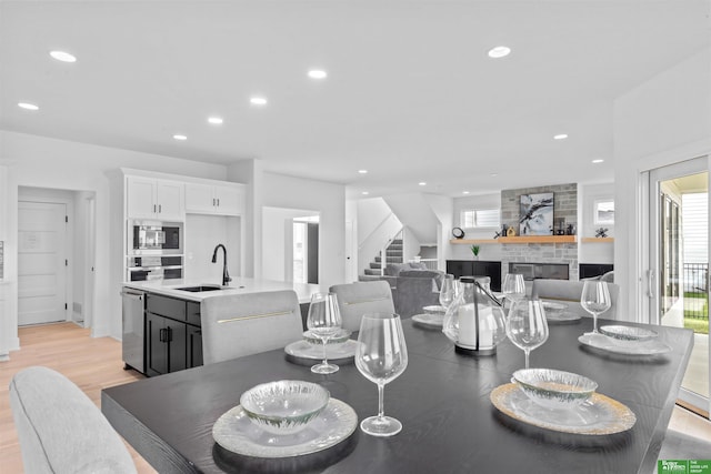 dining room with sink, a fireplace, a healthy amount of sunlight, and light wood-type flooring