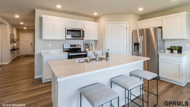 kitchen featuring stainless steel appliances, an island with sink, sink, and white cabinets