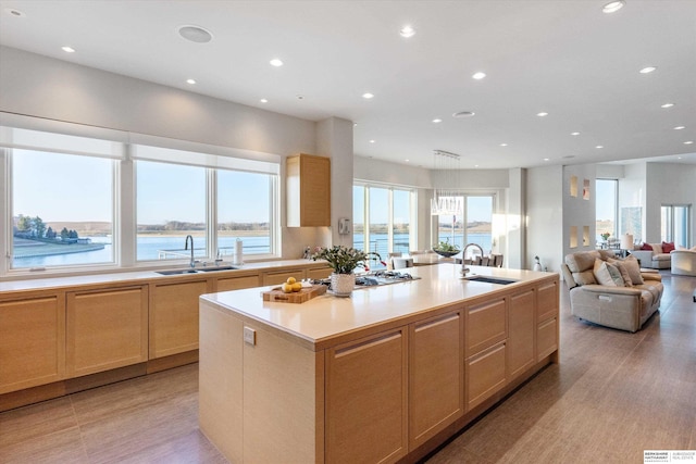 kitchen featuring sink, a kitchen island with sink, and light brown cabinetry