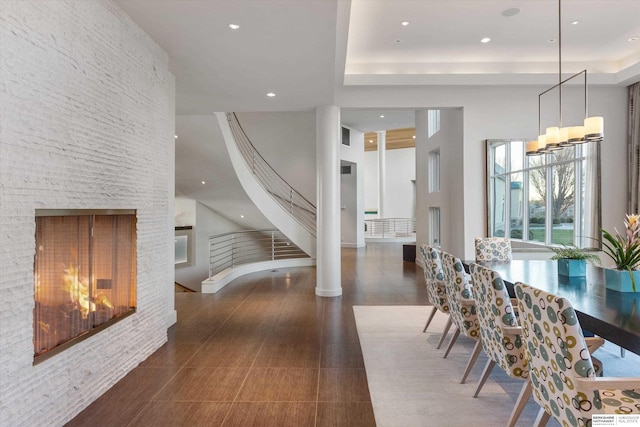 dining space with a high ceiling, a multi sided fireplace, an inviting chandelier, and a tray ceiling