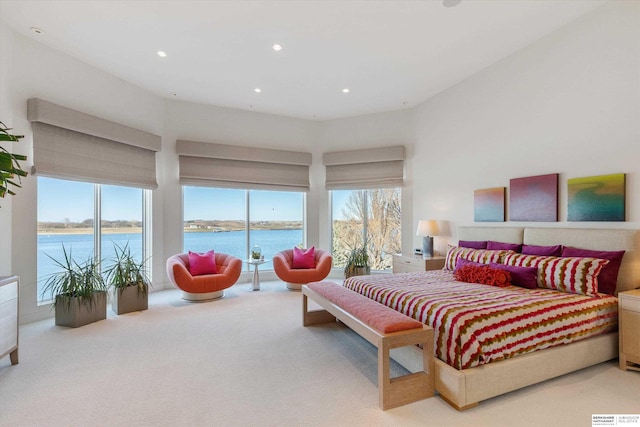 bedroom featuring multiple windows, carpet floors, access to outside, and a water view