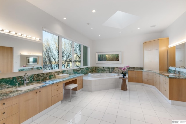 bathroom with tile patterned flooring, vanity, a skylight, and tiled bath