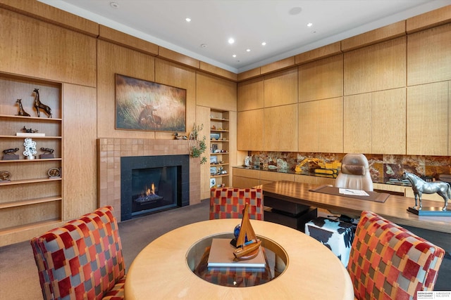 dining space with built in shelves, a tile fireplace, and dark colored carpet