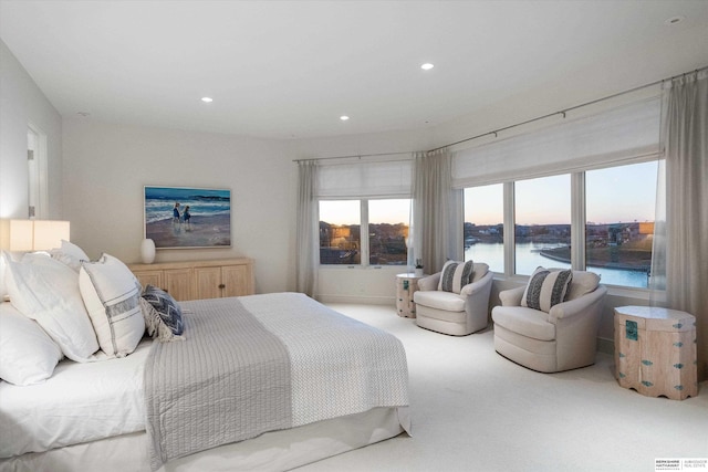 bedroom with a water view and light colored carpet