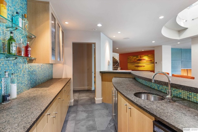 kitchen featuring tasteful backsplash, sink, light brown cabinets, and dark stone counters