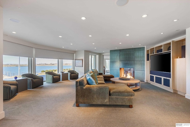 carpeted living room with a water view and a large fireplace