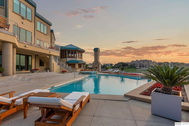 pool at dusk featuring a patio area