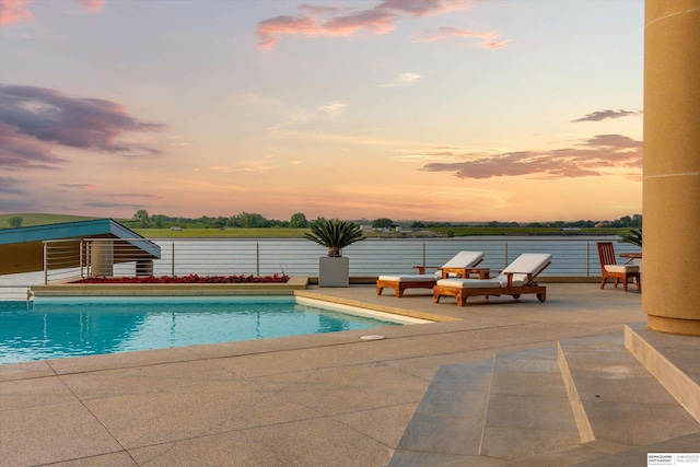 pool at dusk featuring a patio area