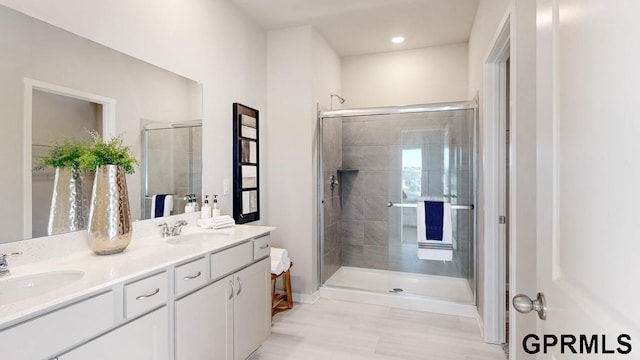 bathroom featuring a shower with door and vanity