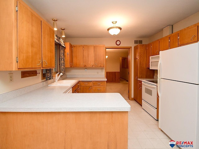 kitchen with white appliances, kitchen peninsula, and sink