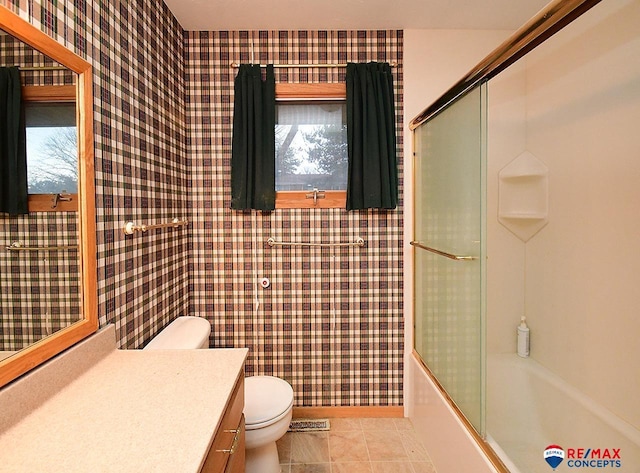 full bathroom with toilet, tile patterned floors, vanity, and shower / bath combination with glass door